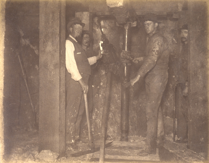 Mt Con 400 level East sill floor breast. Showing Supt. Carroll and drilling machine in act of drilling ore breast