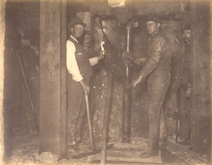 Mt Con 400 level East sill floor breast. Showing Supt. Carroll and drilling machine in act of drilling ore breast